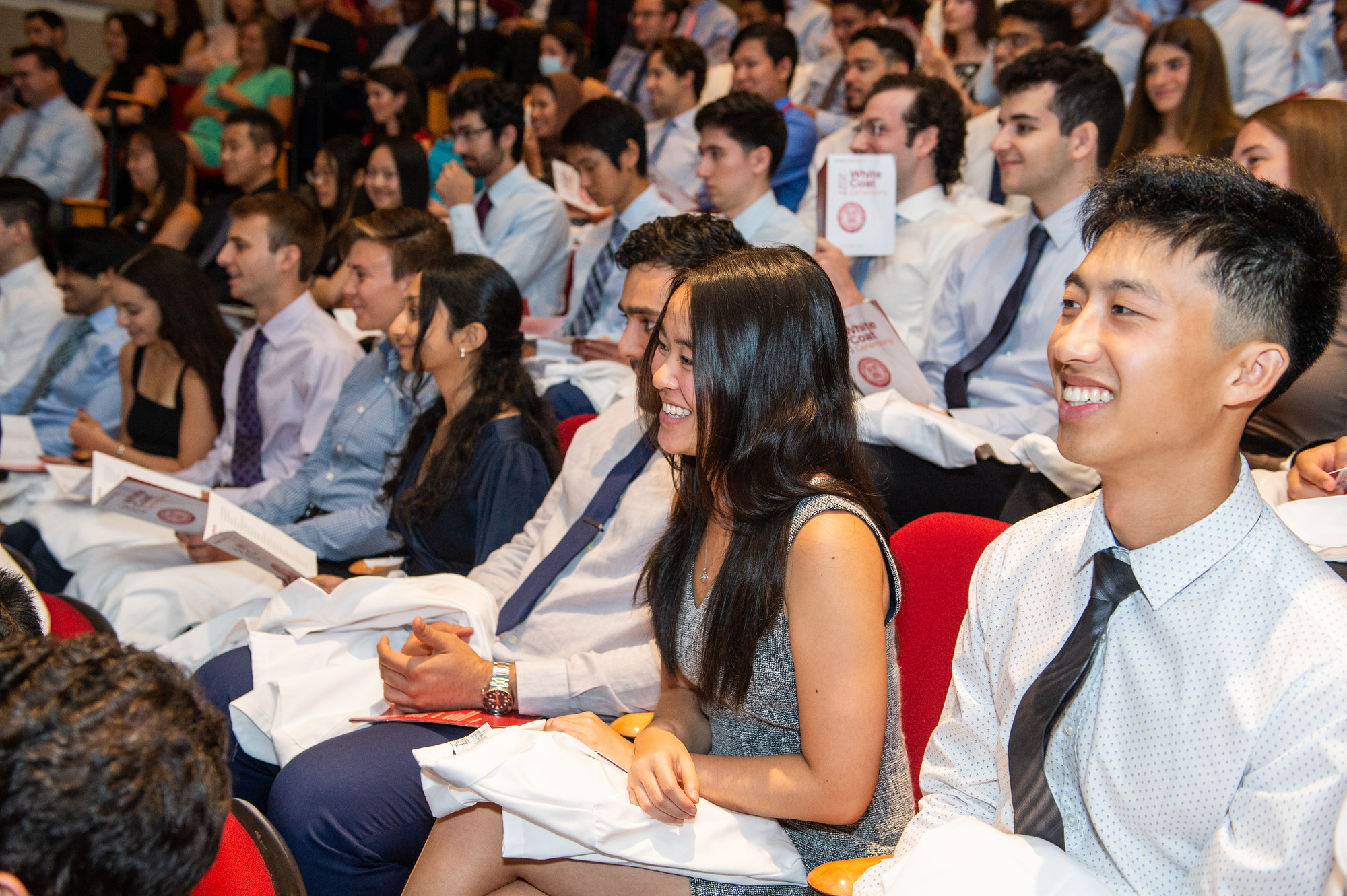 students smiling while seated in the audience 