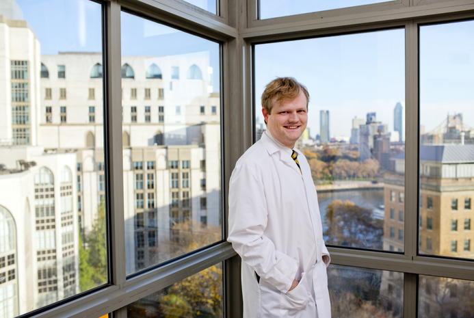 a man in a white coat posing for a picture in a lab