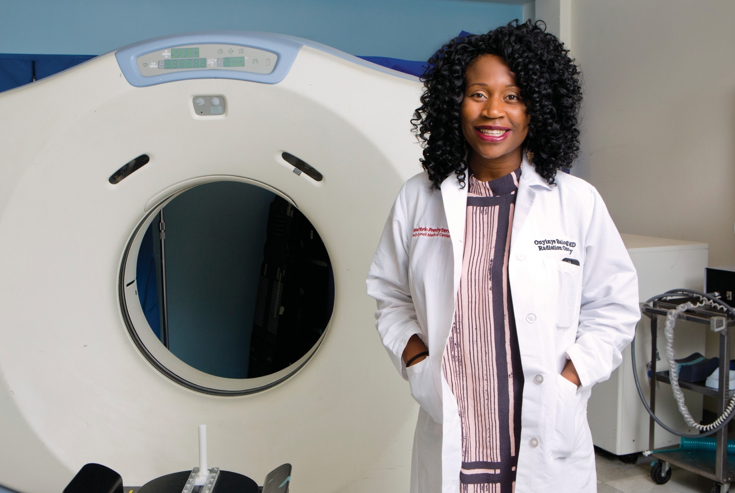 a woman smiling for a portrait in front of an mri