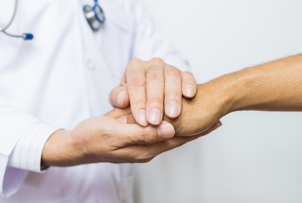stock image of a physician holding a patients hand