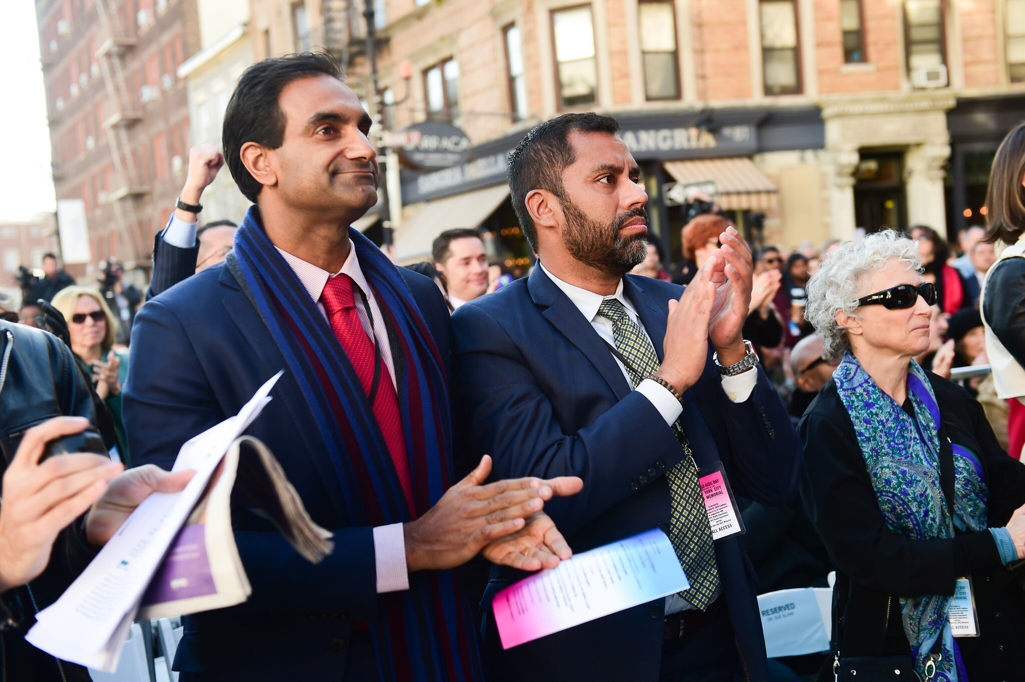 a man clapping outside amongst a crowd of people