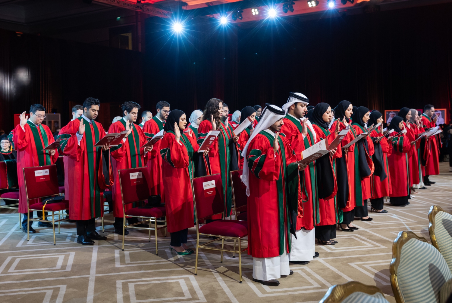 Students wearing graduation regalia giving an oath