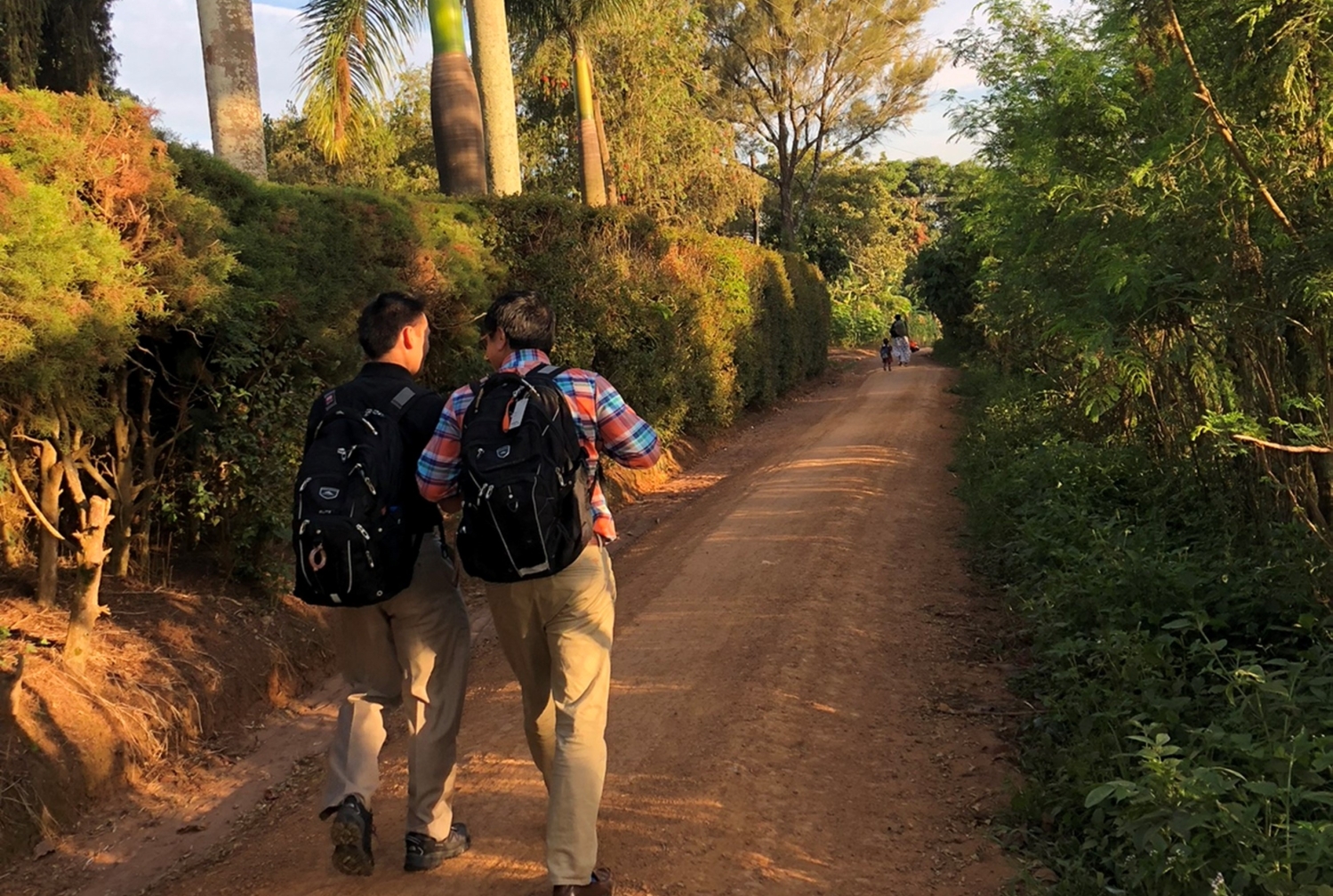 two men walk together down a dirt path
