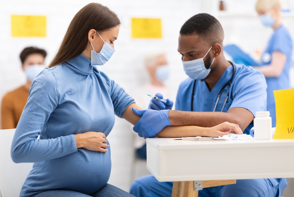 a male doctor giving a vaccine to a pregnant woman