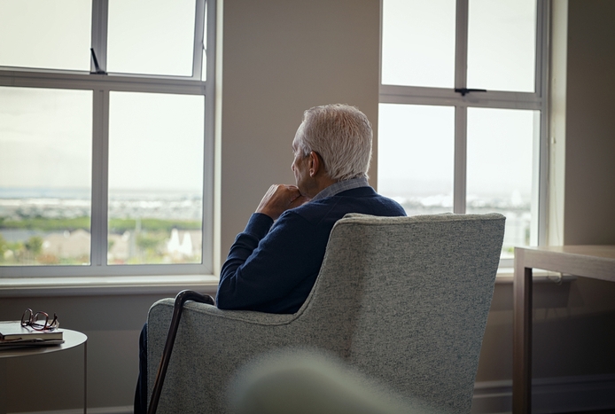 older man sitting in chair looking out the window