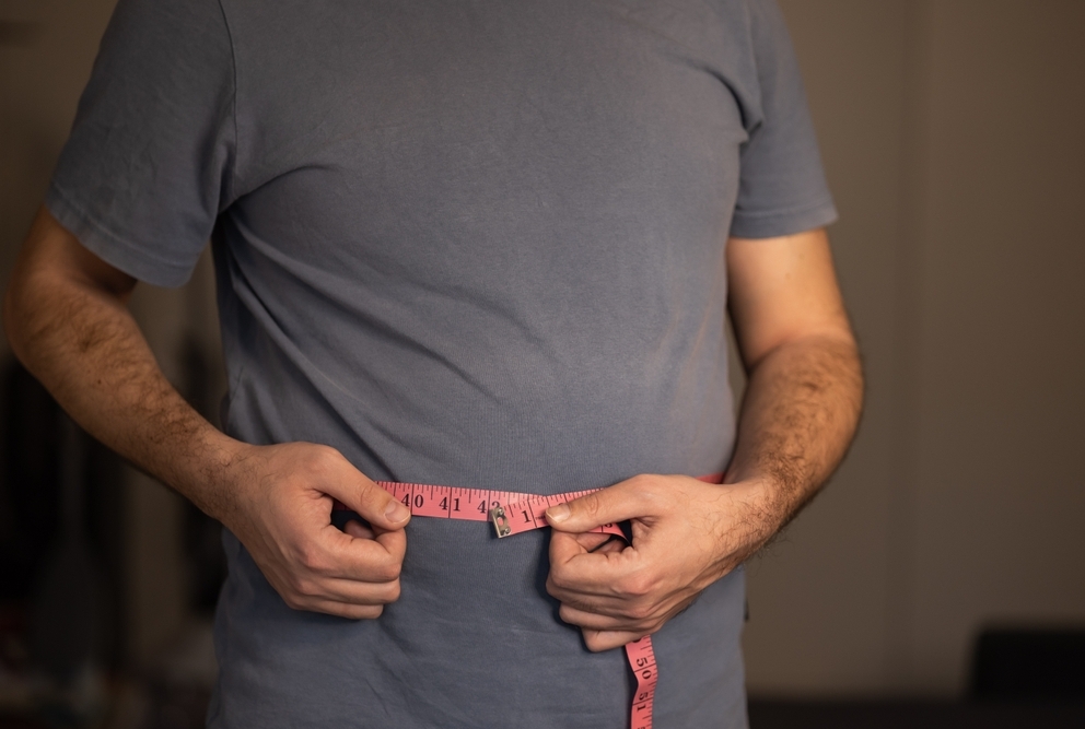 man in a t-shirt holding a tape measure around his waist