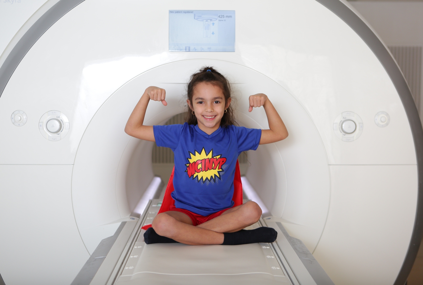 A young girl poses in an MRI machine