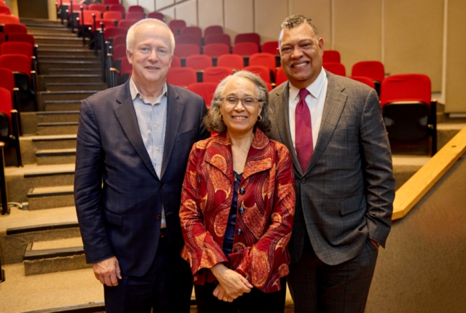 two men standing next a woman in an auditorium