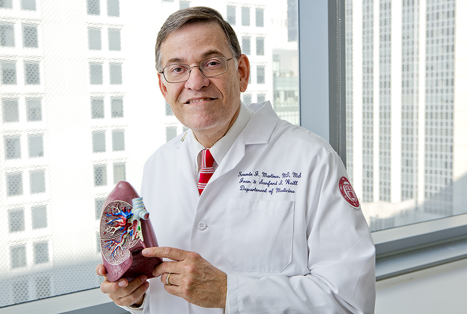 photo of man holding model of lungs
