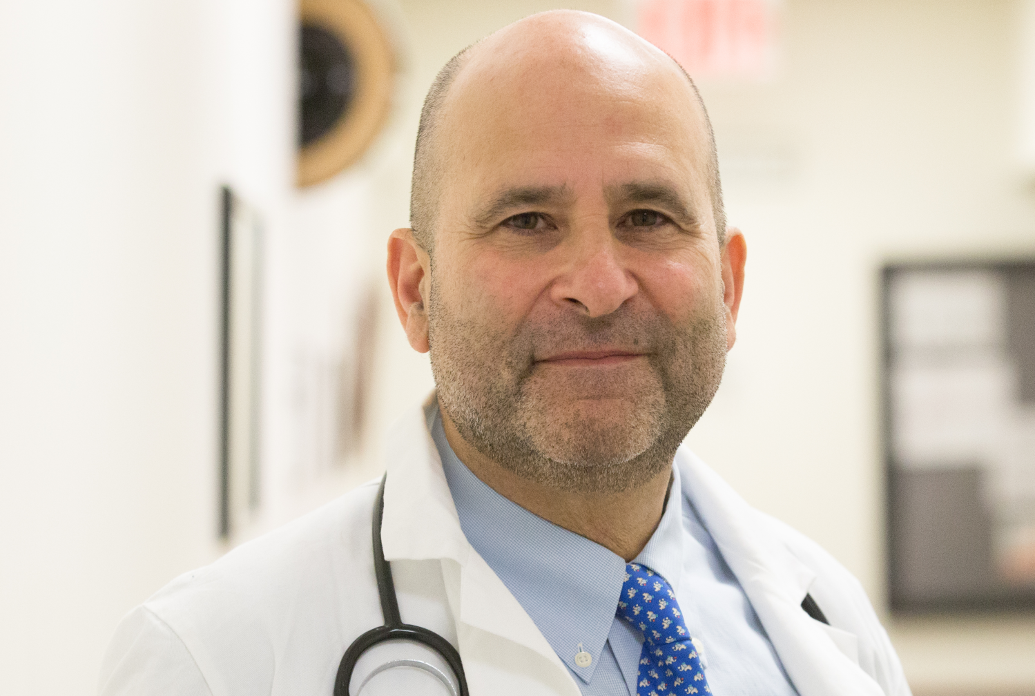 Photo of a male doctor wearing a white coat with a stethoscope around his neck
