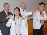 Yifan Xu and Ray Wu receive their white coats from Dean Antonio Gotto and Dr. Peter Marzuk