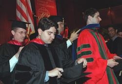 Faculty assist M.D. and Ph.D. students in donning the "hoods" that signify the doctoral degree.
