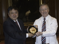 Dr. Dong presents Dean Gotto with a plate featuring a variety of traditional Chinese masks.