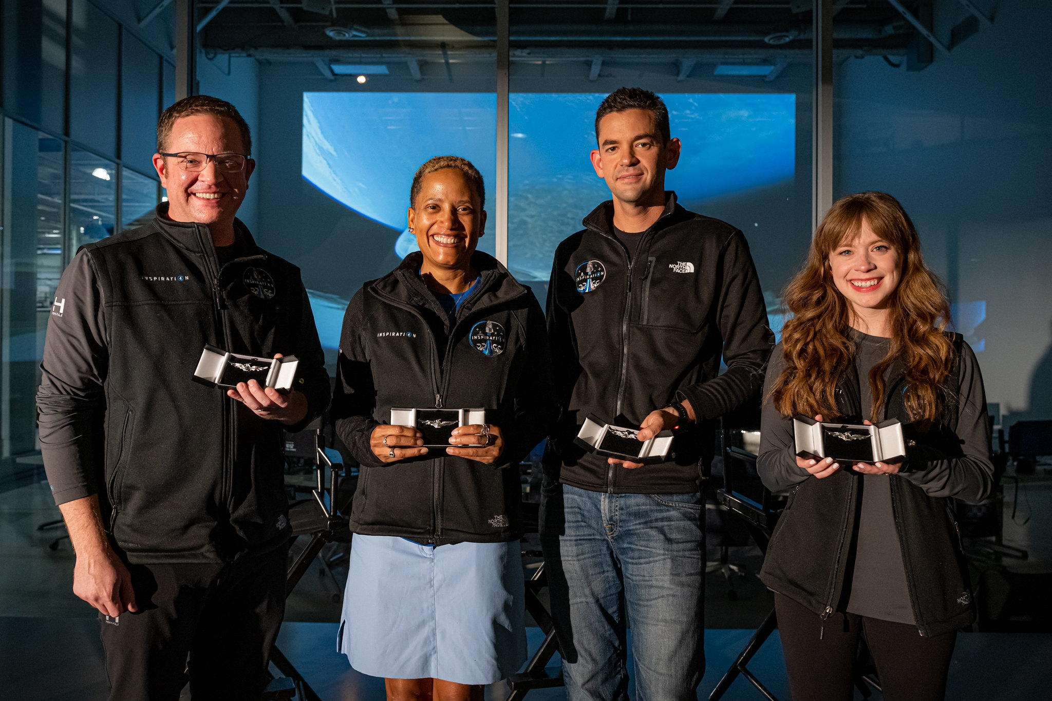 photo of four civilian space travelers in front of NASA building holding wing pins