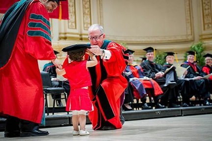 Dr. Dakotah Lane receives his degree from President David Skorton with his daughter 