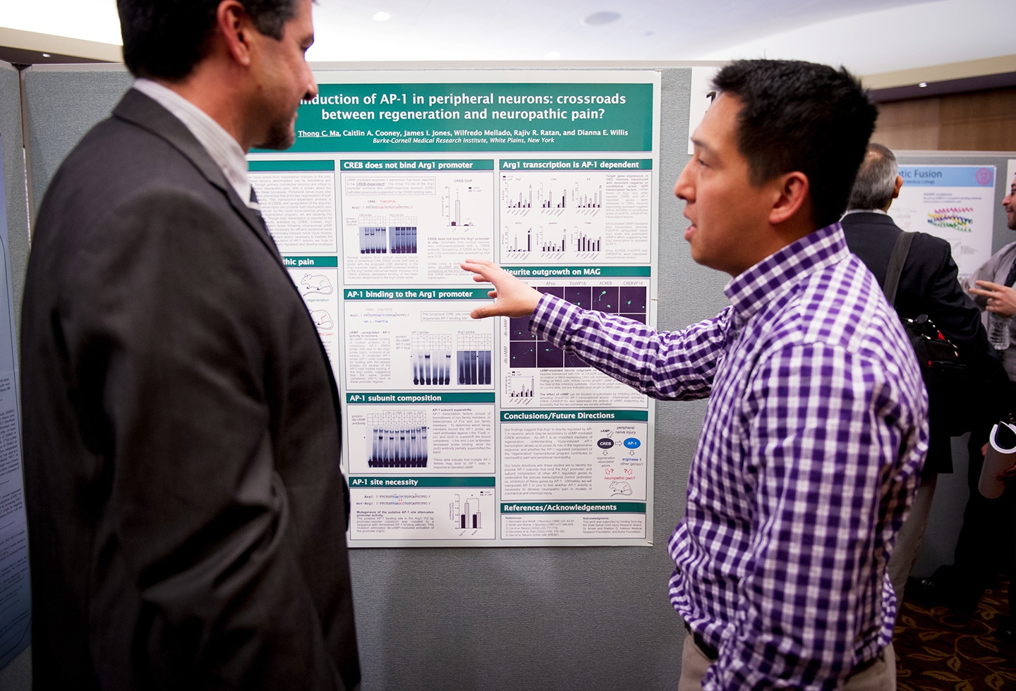 Postdoctoral Associate Dr. Thong Ma, right, presents his poster, "Induction of AP--1 in peripheral neurons: crossroads between regeneration and neuropathic pain?," to Dr. Andy Giovanni, translational medicine expert at the pharmaceutical company Sanofi. Dr. Thong Ma presents poster "Induction of AP--1 in peripheral neurons: crossroads between regeneration and neuropathic pain?" to Dr. Andy Giovanni