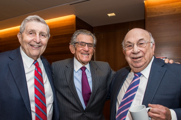 Three men pose for a photo at an event.