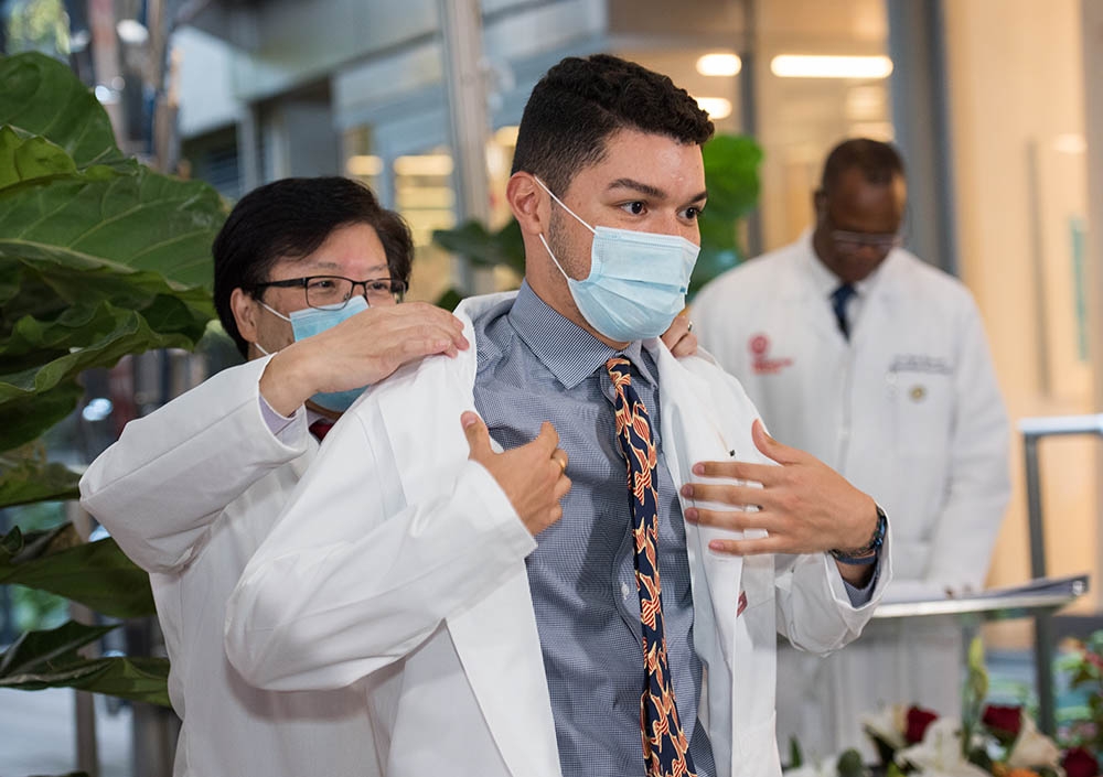 Dr. Augustine Choi coats a student