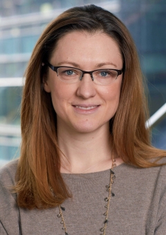 A woman with straight hair and glasses smiling for a portrait