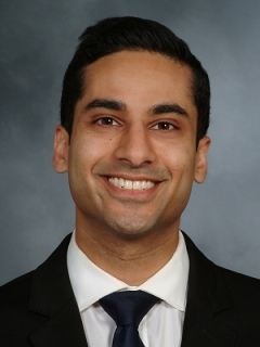 a brown skinned man posing for a headshot.