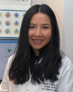 a fair-skinned woman with long black hair, sitting in a lab