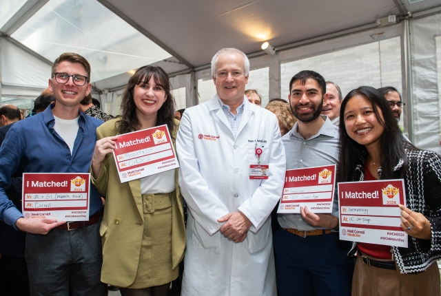 Dean Robert Harrington posing with students holding match signs